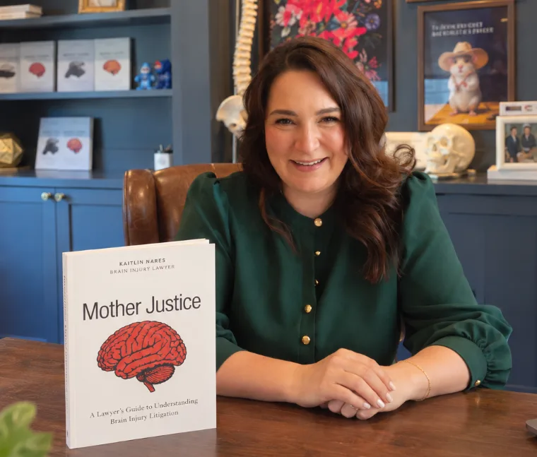 Kaitlin Nares at her desk with a copy of Mother Justice
