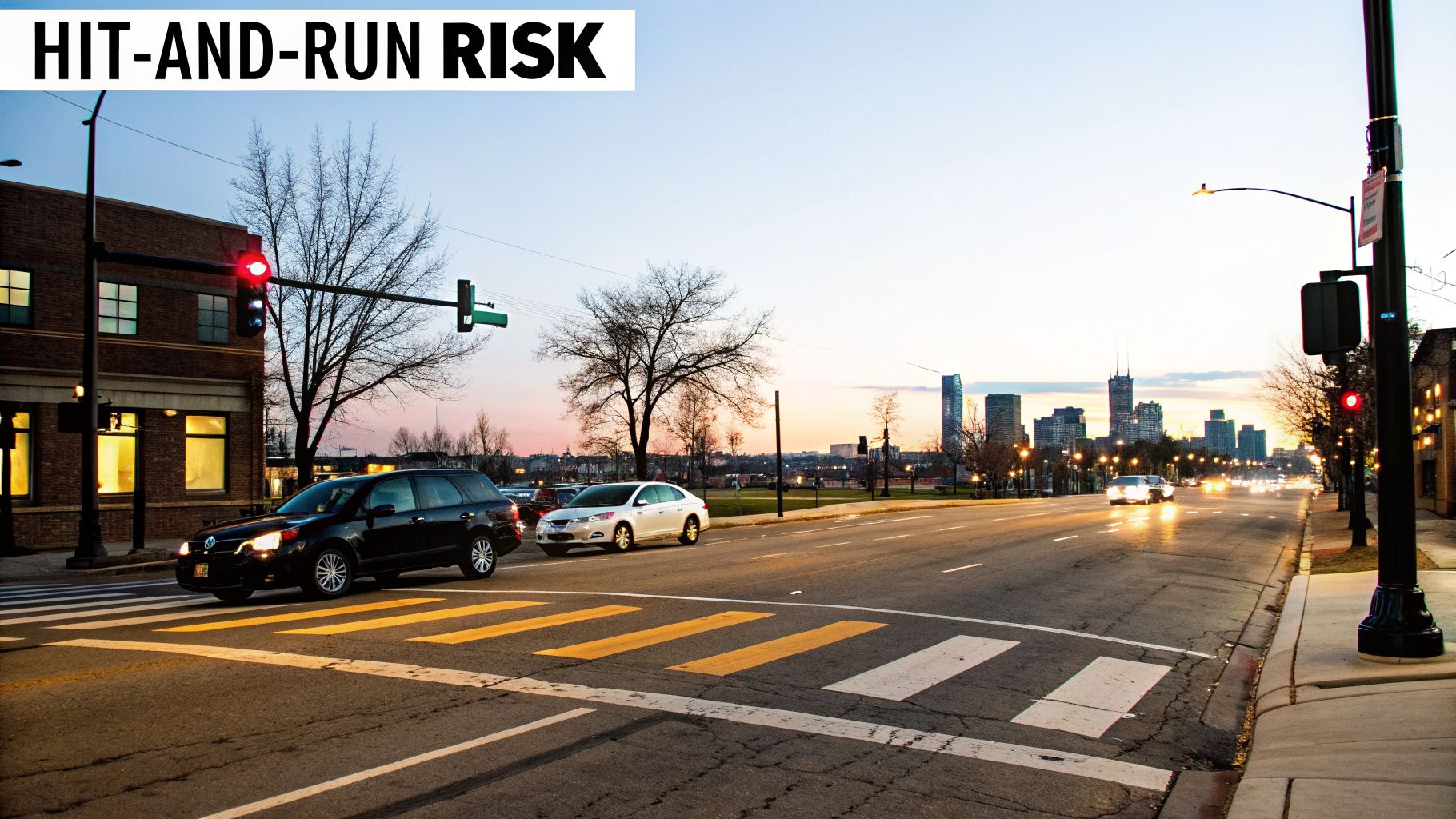 Urban street at dusk with cars, crosswalk, traffic lights, and city skyline, addressing hit-and-run risk.