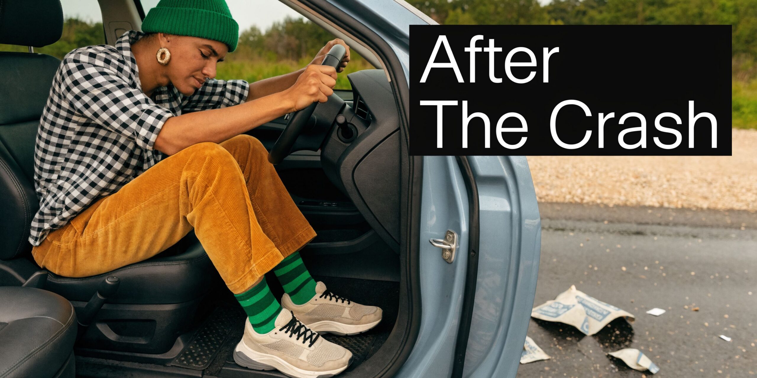 A person sitting stressed behind the steering wheel of a car after a road accident occurred.