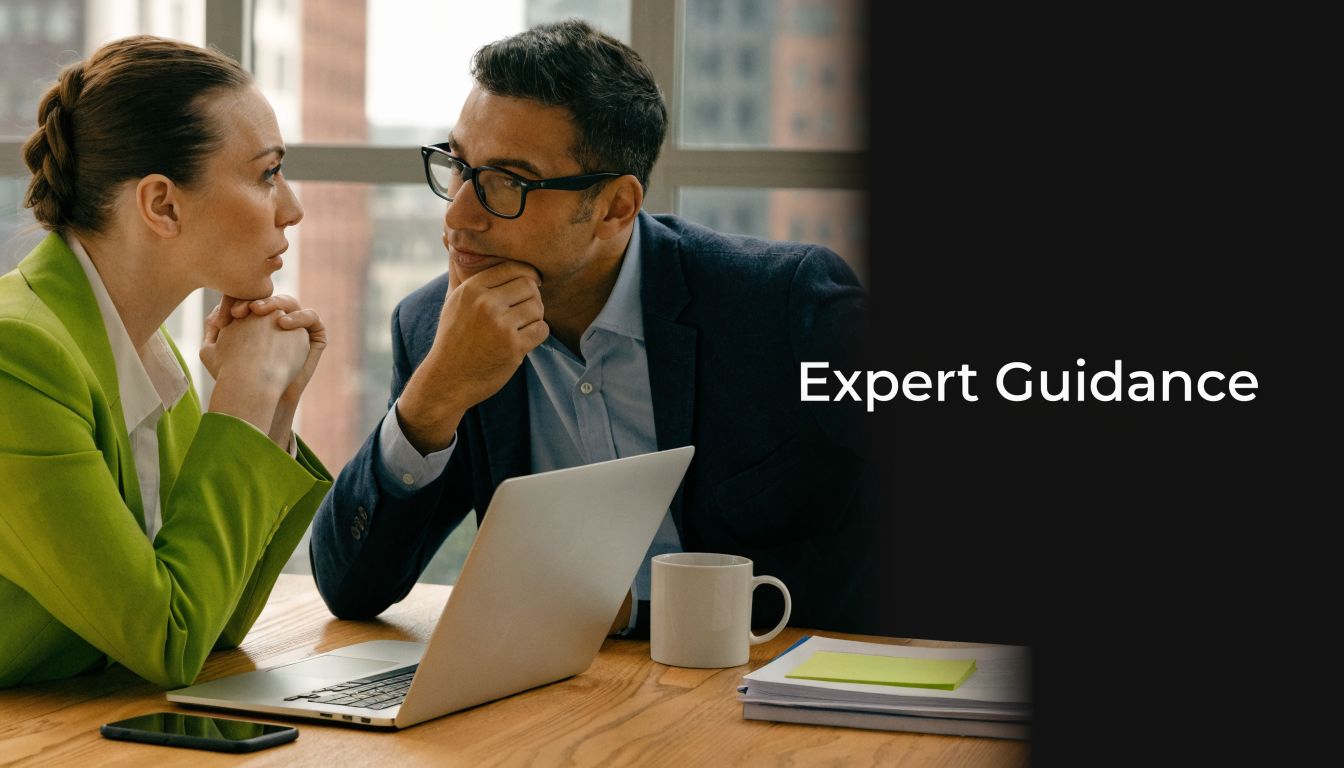 A professional man and woman discussing business strategy while looking at a laptop in an office.