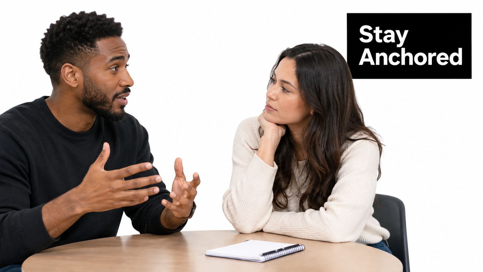 A man and woman having a serious professional discussion at a table with a notepad.